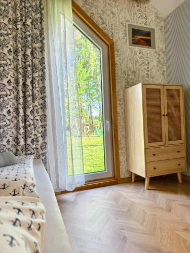 a bedroom with a window and a bed and a dresser at Bosko beztrosko in Dębki