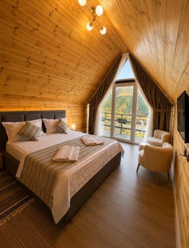 a bedroom with a large bed and a large window at Guest house Panorama in Koman