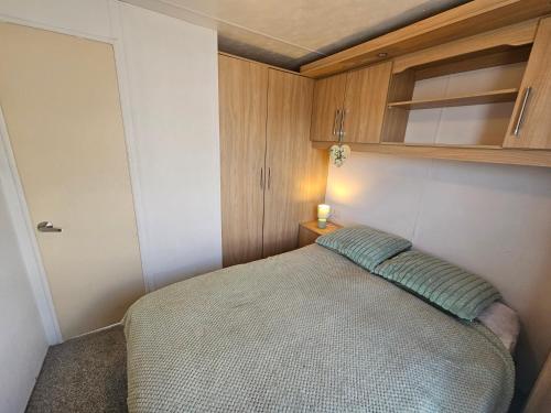 a small bedroom with a bed and wooden cabinets at 3 bed static van with decking in Dymchurch