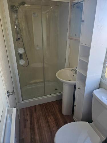 a bathroom with a shower and a sink and a toilet at 3 bed static van with decking in Dymchurch
