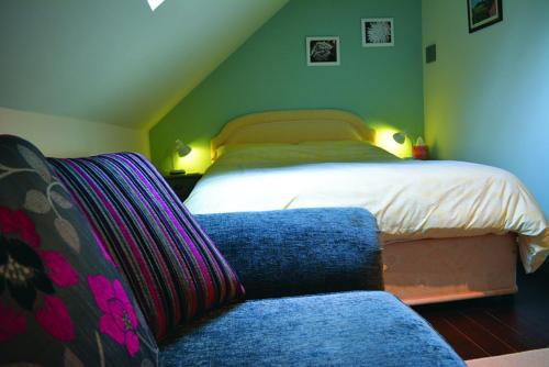 a bedroom with a bed and a blue couch at Old Coach House Studio in Highley