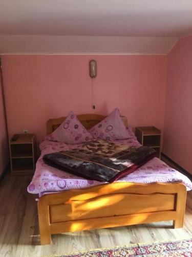 a bed in a room with a pink wall at Casa Flory nr 2- Complex de Pensiuni si Casute la Munte in Bistricioara