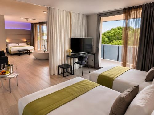a hotel room with two beds and a television at HOTEL VENICE BEACH HVB 34 Lifestyle 4 Superior in Bibione