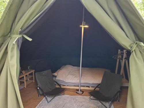 a room with a bed in a tent with two chairs at Green woodland bell tent in Ynys Station
