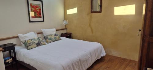 a bedroom with a white bed with two pillows at Le Peyroutet in Cazaux-Villecomtal