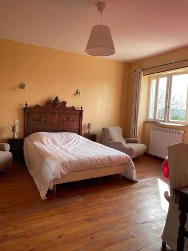 a bedroom with a bed and a chair and window at BOISSET, Grande maison familiale avec vue sur les Pyrénées in Castel-Sarrazin
