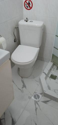 a white bathroom with a toilet and a sign on the wall at Cosy apartment in Perea