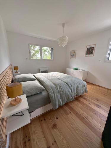 a white bedroom with a large bed and a chair at Maison en bois moderne in Pléneuf-Val-André