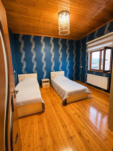 two beds in a room with blue walls and wooden floors at Green dream House in Lankaran