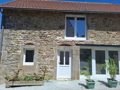 a stone house with a white door and windows at Faugere in Bussières