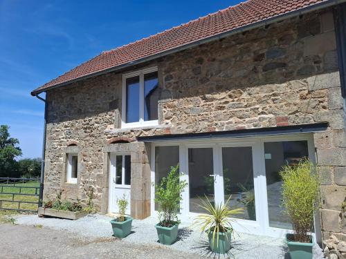 a stone house with large windows and potted plants at Faugere in Bussières