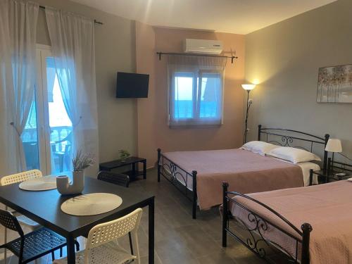 a hotel room with two beds and a table and chairs at Tsatsoni Studios in Velika