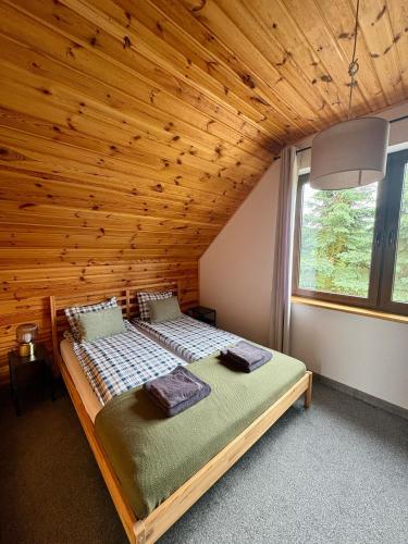 a bed in a room with a wooden ceiling at SOCHÓWKA nad Jeziorem Skarlińskim in Kurzętnik