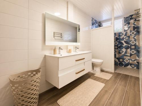 a bathroom with a sink and a toilet and a mirror at Villa Coralys - Plage - Cozy in Schœlcher