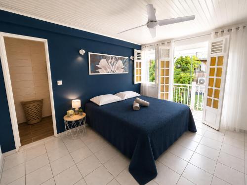 a blue bedroom with a bed with a blue wall at Villa Coralys - Plage - Cozy in Schœlcher