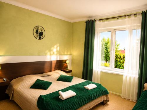 a bedroom with a bed with green sheets and a window at Diófa Apartman Balatonederics in Balatonederics