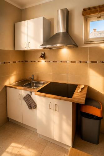 a kitchen with white cabinets and a sink at Diófa Apartman Balatonederics in Balatonederics
