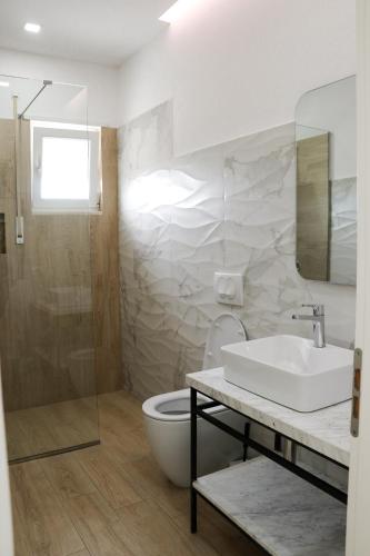 a white bathroom with a sink and a toilet at Airen Hotel Velipoje in Velipojë