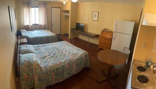 a room with two beds and a table and a refrigerator at Pine Creek Motel in Waskatenau