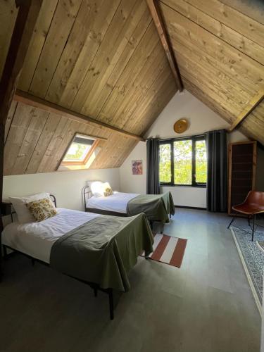 two beds in a room with wooden ceilings at Atelier Onder de Notenboom in Appeltern