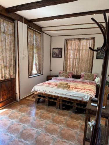 a bedroom with a bed and two windows at Old Court in Curtea de Argeş