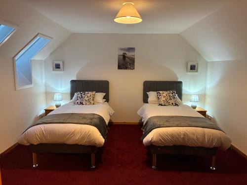 two beds in a room with two windows at Lotties Neuk in Lerwick