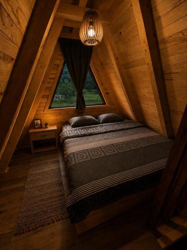 an attic bedroom with a bed and a window at Vikendica Ema in Šipovo