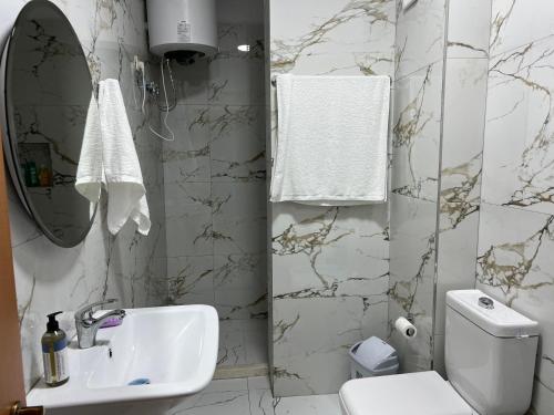 a white bathroom with a sink and a toilet at Garden view apartment in Karpen