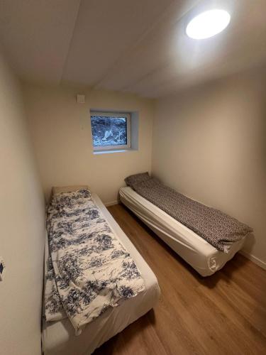 two beds in a small room with a window at Abildsø Apartment in Oslo