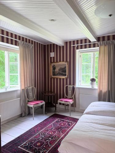 a bedroom with a bed and two chairs and windows at Kronovall Park Residence in Skåne-Tranås
