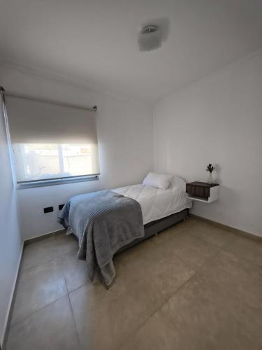 ein weißes Schlafzimmer mit einem Bett und einem Fenster in der Unterkunft Aloha 3 in Chacabuco
