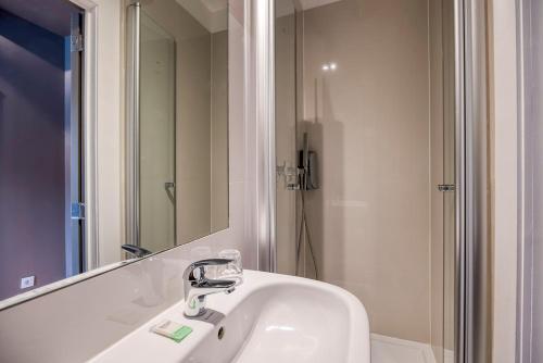 ein Badezimmer mit Waschbecken, Spiegel und Dusche in der Unterkunft Hotel The Neufchatel in Brüssel