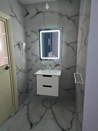 a marble bathroom with a sink and a mirror at Hotel Restorant Genti Peshkatari in Orikum
