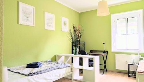 a bedroom with green walls and a white bed in it at Geräumiges & helles Apartment nahe Leipzig in Böhlen