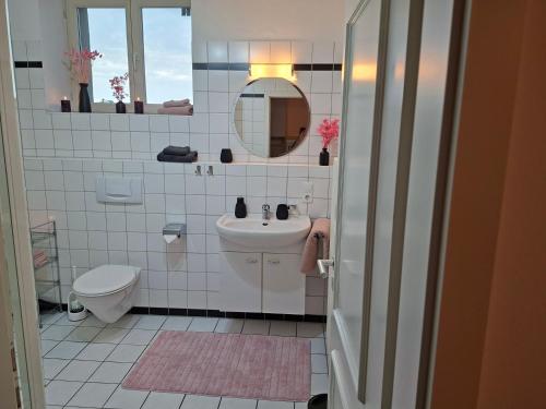 a bathroom with a sink and a toilet and a mirror at Rosarote Insel - La Vie en Rose in Lindau