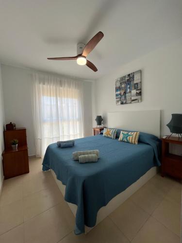 a bedroom with a blue bed with a ceiling fan at ÁTICO Paraíso Beach con piscina privada in Vera