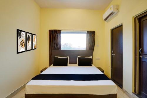 a bedroom with a large bed with a window at Hotel O Maa JP Tower in Jabalpur