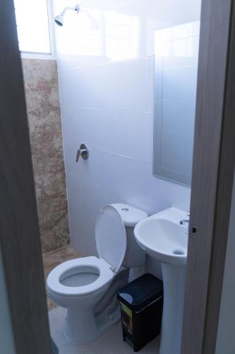 a white bathroom with a toilet and a sink at Casa Rafaela in Santa Elena