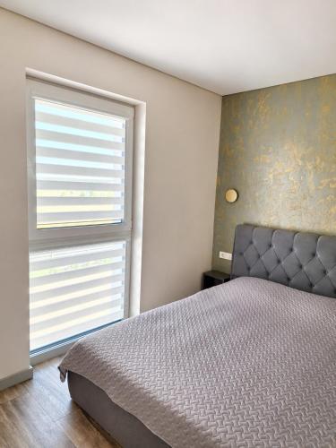 a bedroom with a bed and a large window at Kregždžių apartamentai in Šventoji