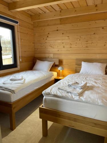two beds in a room with wooden walls at Kozara Panoramic Resort in Bosanska Gradiška