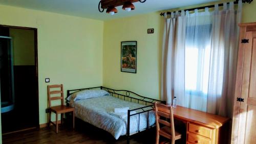 um quarto com uma cama, uma secretária e uma janela em El Pozo de la Cotarra em Cabezuela