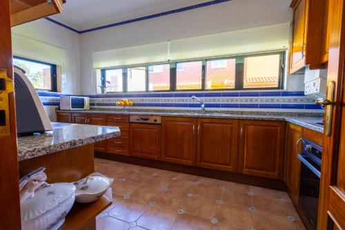 a kitchen with wooden cabinets and a counter top at Villa Fernandos in Praia de Mira