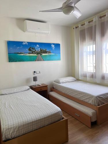 a bedroom with two beds and a painting on the wall at Villa Sonrisa de Oro - private swimming pool in Miami Platja