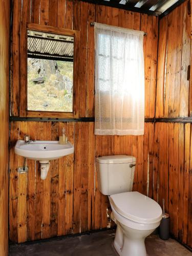 a bathroom with a toilet and a sink and a window at Glocke Mountain Camp in Outjo