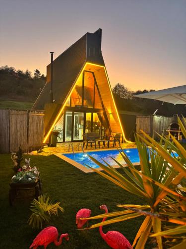 a house with a triangular roof with flamingos in the yard at Banderabungalov in Kartepe