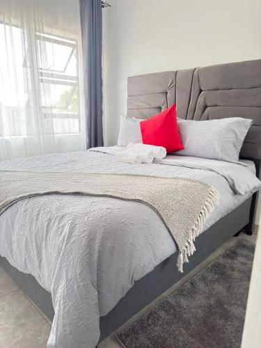 a bed with a red pillow on top of it at Palmview in Bulawayo