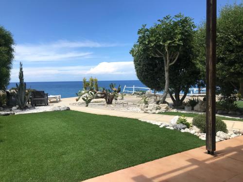 a garden with green grass and the ocean in the background at Boutique seafront apartment in Saint Amvrosios