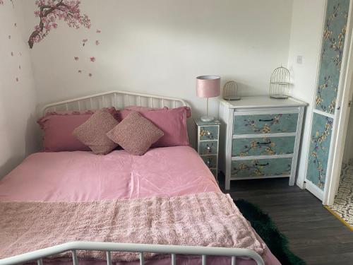 a bedroom with a pink bed and a night stand at Comfortable Guesthouse Stratford upon avon in Stratford-upon-Avon