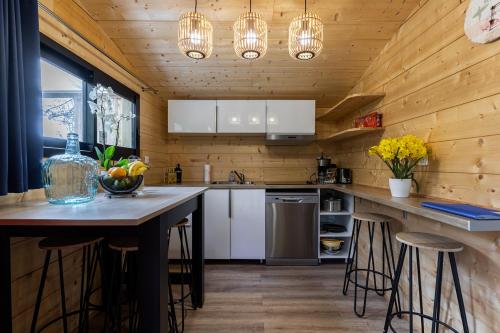 a kitchen with wooden walls and white cabinets and bar stools at Village Nature et Océan à côté de la plage avec piscine et jacuzzi in Messanges