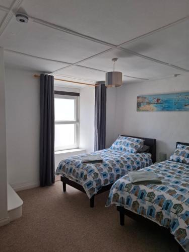 a bedroom with two beds and a window at 17 French Street in Teignmouth